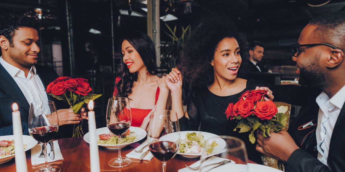 Friends in a Restaurant Enjoying Romantic Evening. Group Happy Friends Enjoying Dating in Restaurant. Double Couple Dating in Restaurant. Romantic Concept. Bouquet Red Roses. Love Concept.